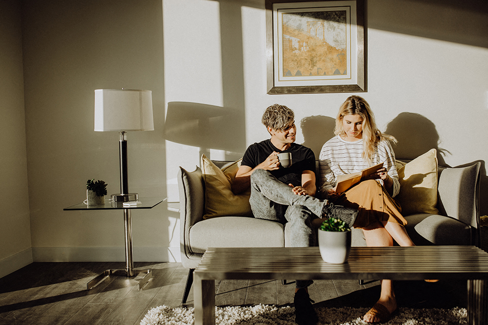 a man and woman sitting on a couch looking at their cell phones