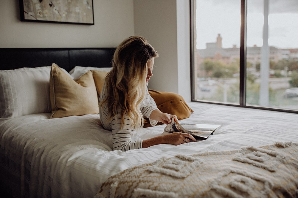 a woman laying on a bed looking at a magazine