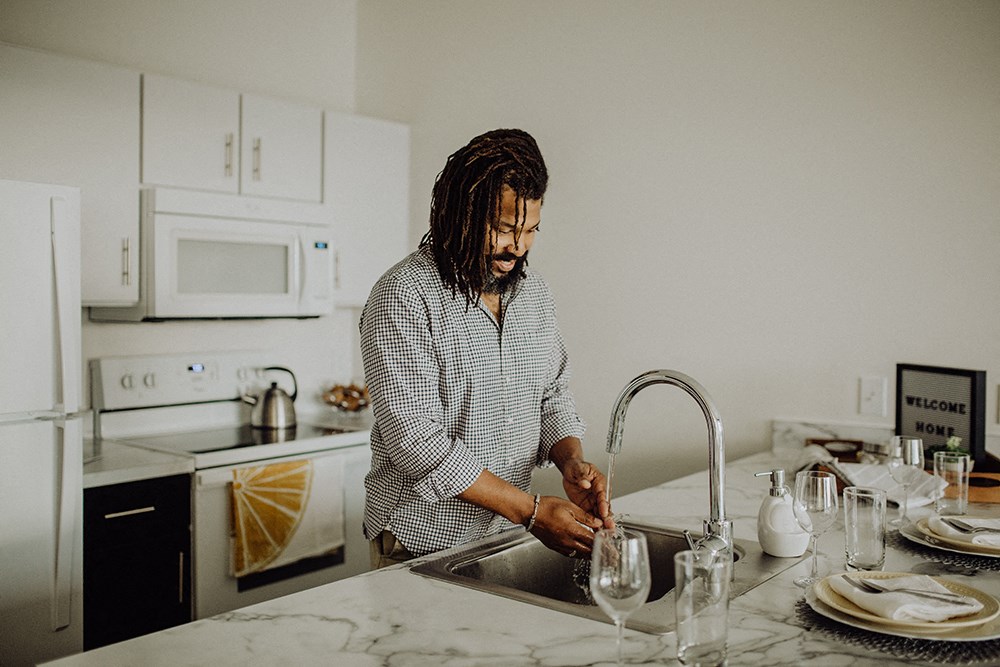 a man washing his hands in the kitchen sink