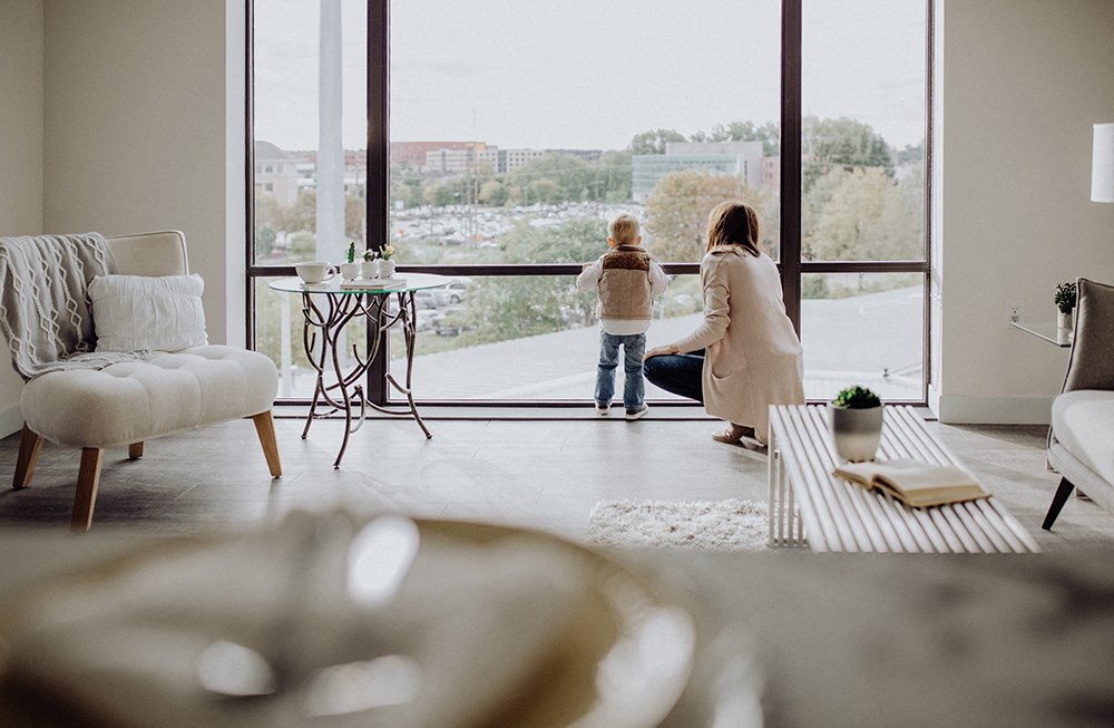 a mother and child looking out the window of a living room