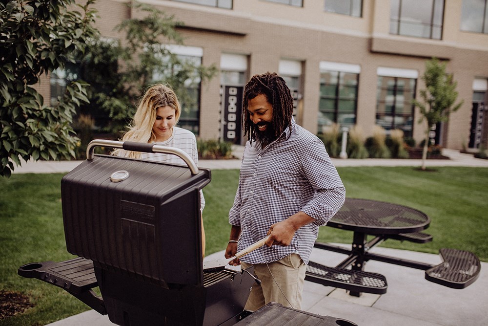 a man and a woman grilling food on a grill