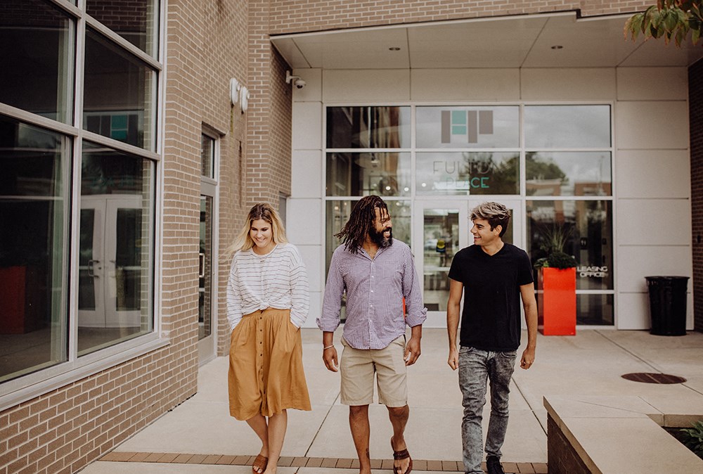 two men and a woman walking outside of a building