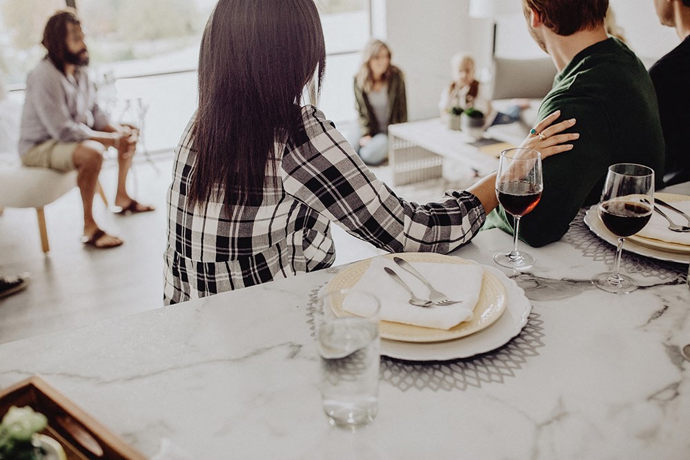 a group of people sitting at a table with food and wine