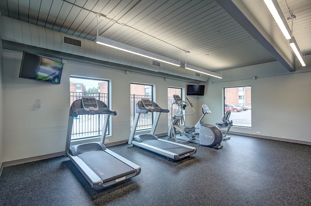 a gym with cardio equipment and windows in a building