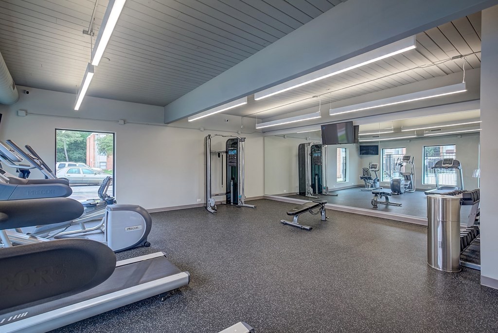 a gym with a lot of machines and chairs and a tv