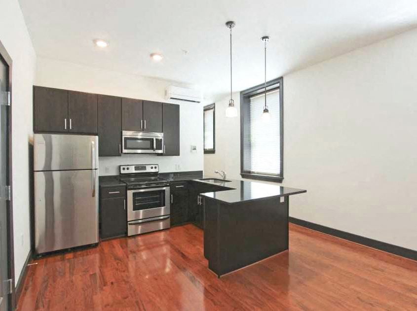 an empty kitchen with stainless steel appliances and wooden floors