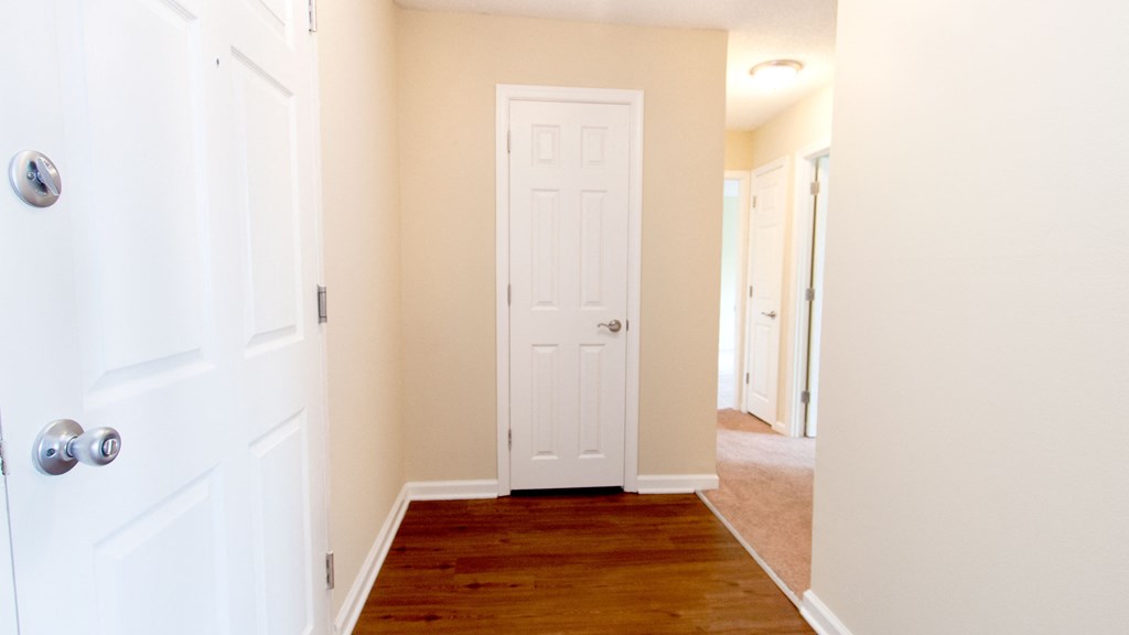 an empty hallway with a white door and a wooden floor