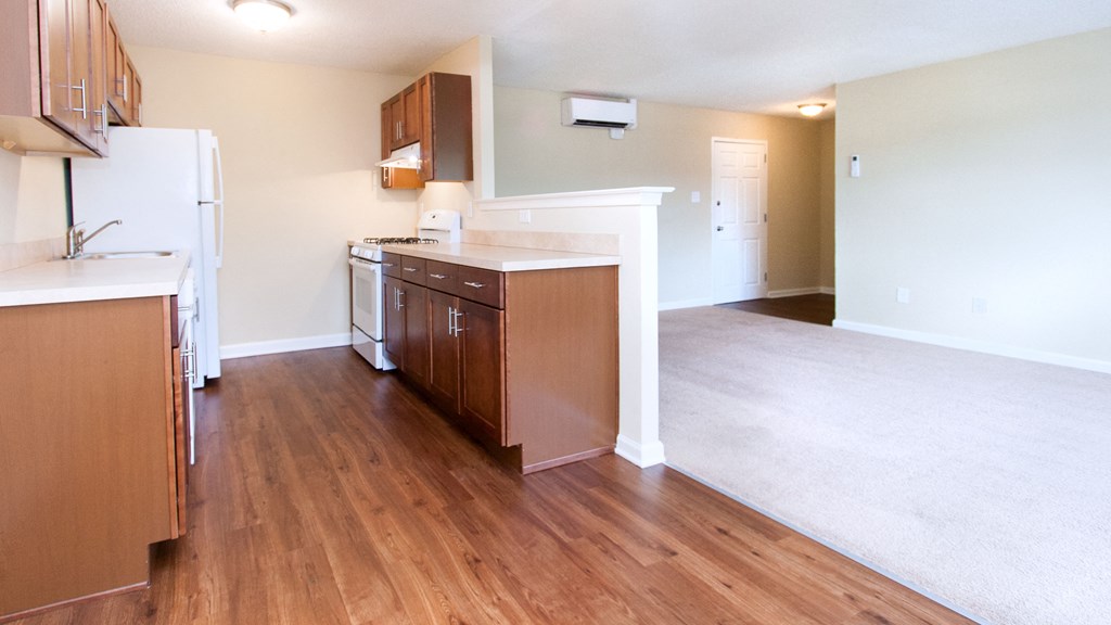 an empty kitchen and living room with wood flooring and white walls