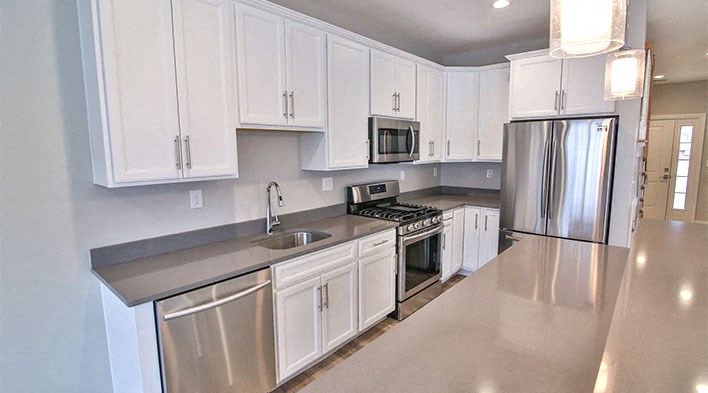 a kitchen with white cabinets and a stainless steel refrigerator
