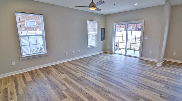 an empty living room with wood floors and a sliding glass door