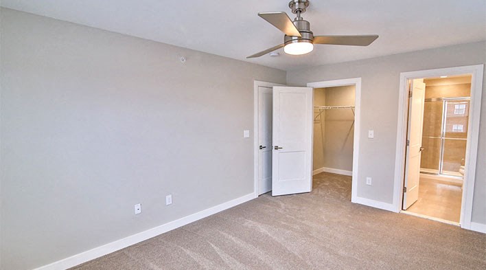 an empty living room with a ceiling fan and a closet