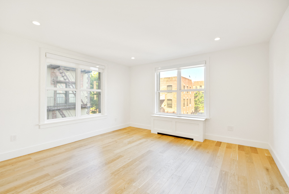 a living room with a hardwood floor and two windows