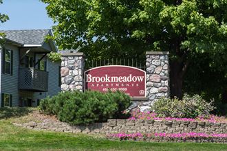 a sign for brookhaven apartments in front of a tree and a stone wall