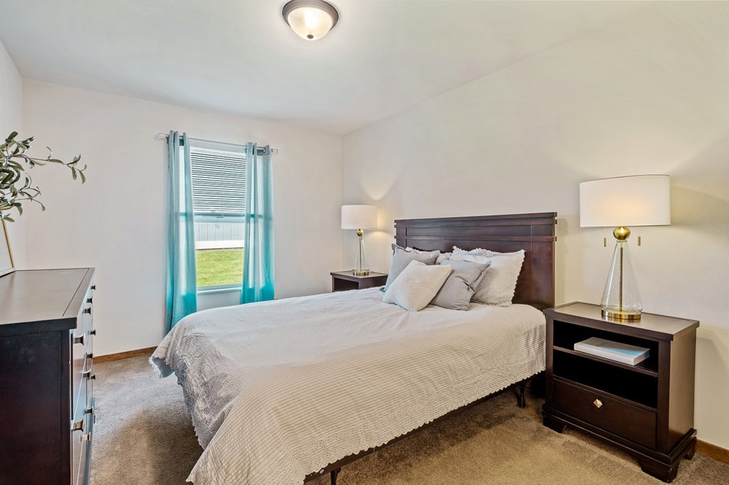 A bedroom with a bed, nightstand, and lamp.