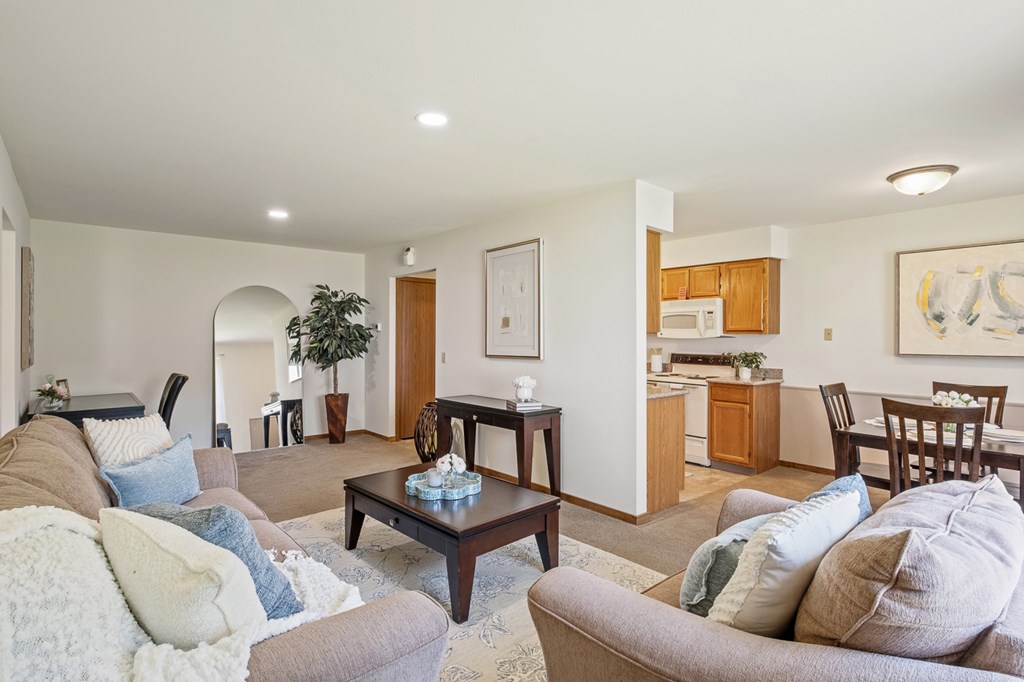 A living room with a couch, a coffee table, and a dining area in the background.