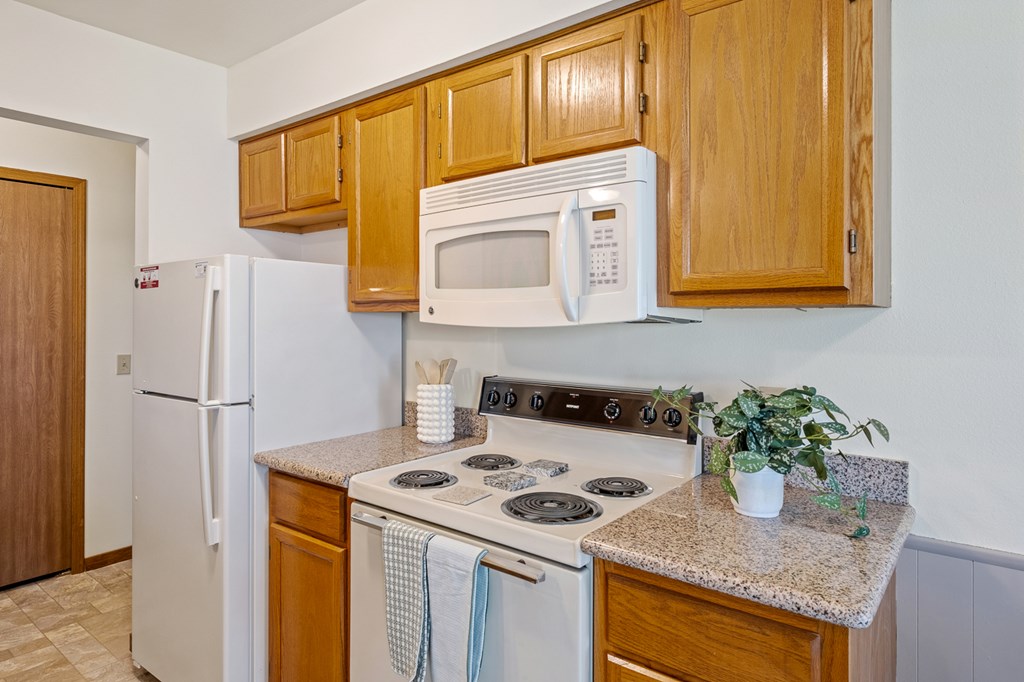 A kitchen with a white stove top oven and a white microwave above it.