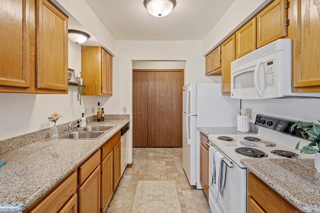 A kitchen with white appliances and wooden cabinets.