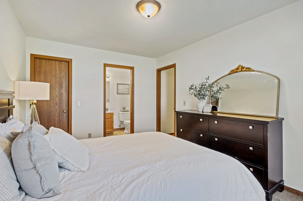 A bedroom with a bed, dresser, and mirror.