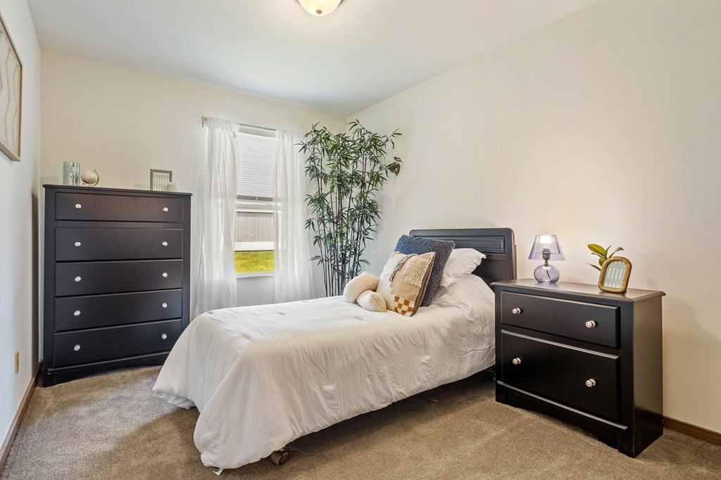 A bedroom with a bed, nightstand, and dresser.