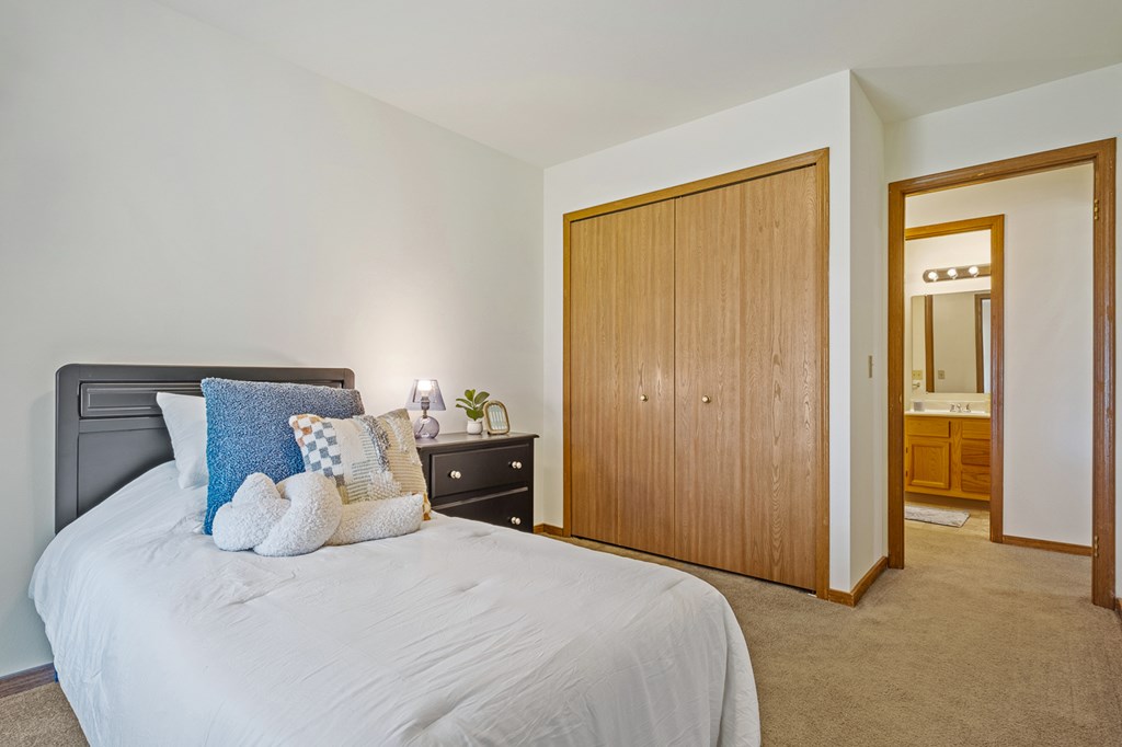 A bedroom with a bed, nightstand, and wardrobe.