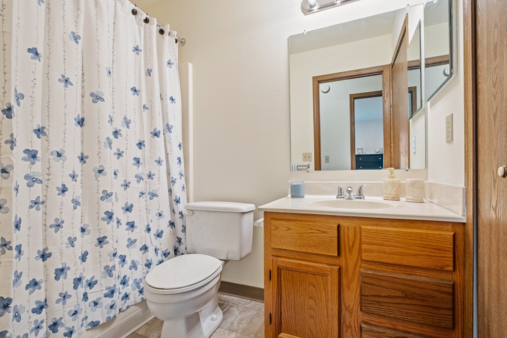 A white toilet with a blue floral shower curtain in a bathroom.