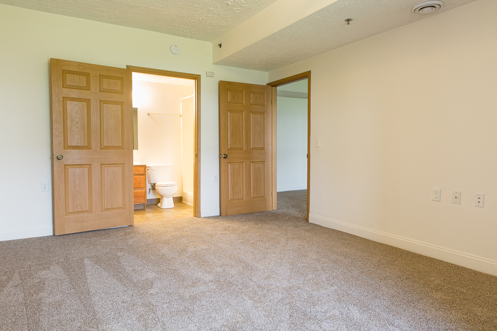an empty living room with two doors and a bathroom