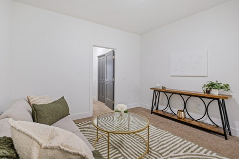 A living room with a sofa, a coffee table, and a painting on the wall.