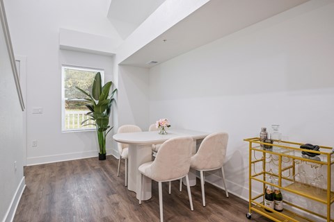 A dining room with a white table and chairs and a yellow cart.