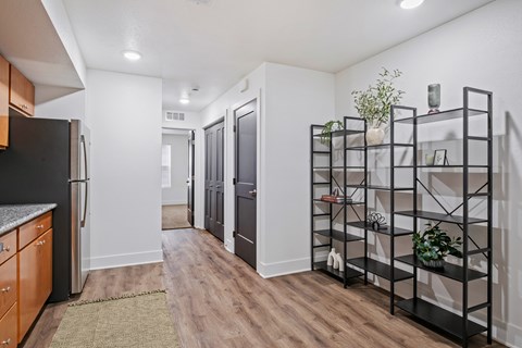 A kitchen with a black refrigerator and wooden floors.