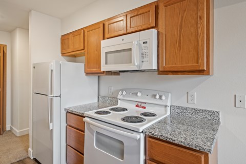 A kitchen with a white stove and microwave above it.