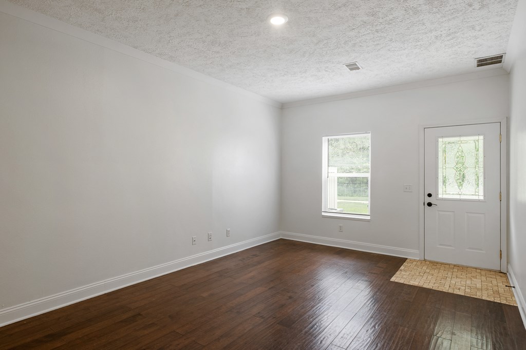 A room with a white door and a window with a view of a tree.