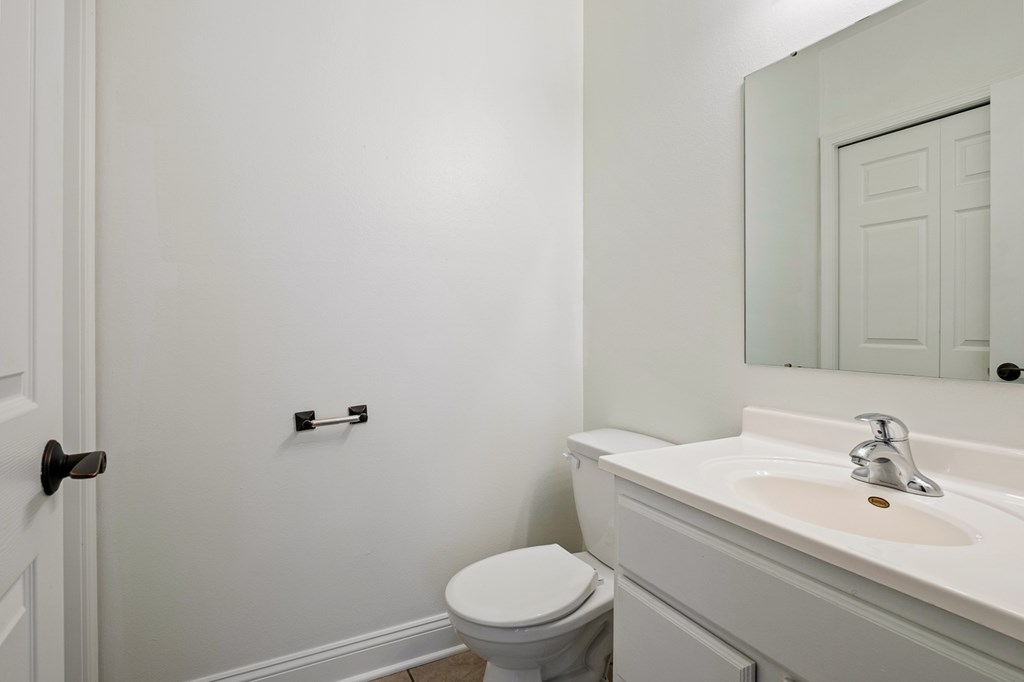 A white toilet sits next to a white sink in a bathroom.