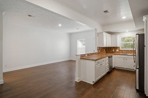 A kitchen with white cabinets and a wooden island.