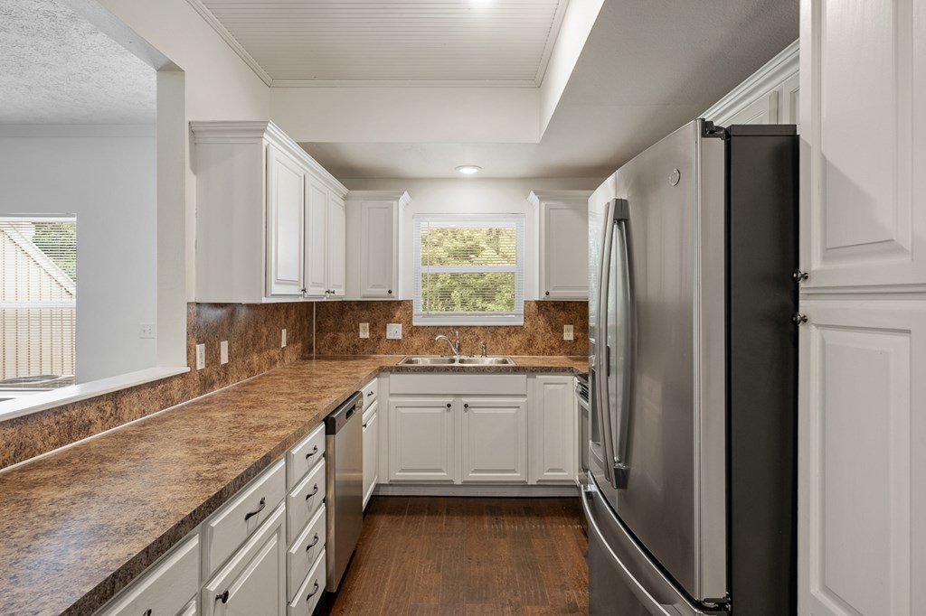 A kitchen with white cabinets and a black refrigerator.