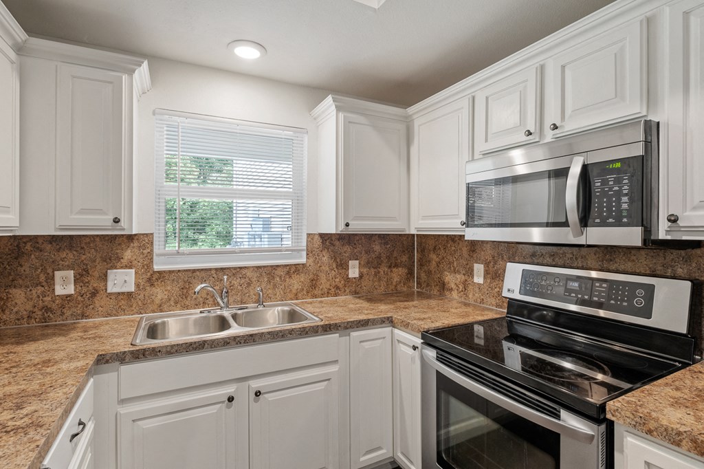 A kitchen with a black stove top oven and a black microwave above it.