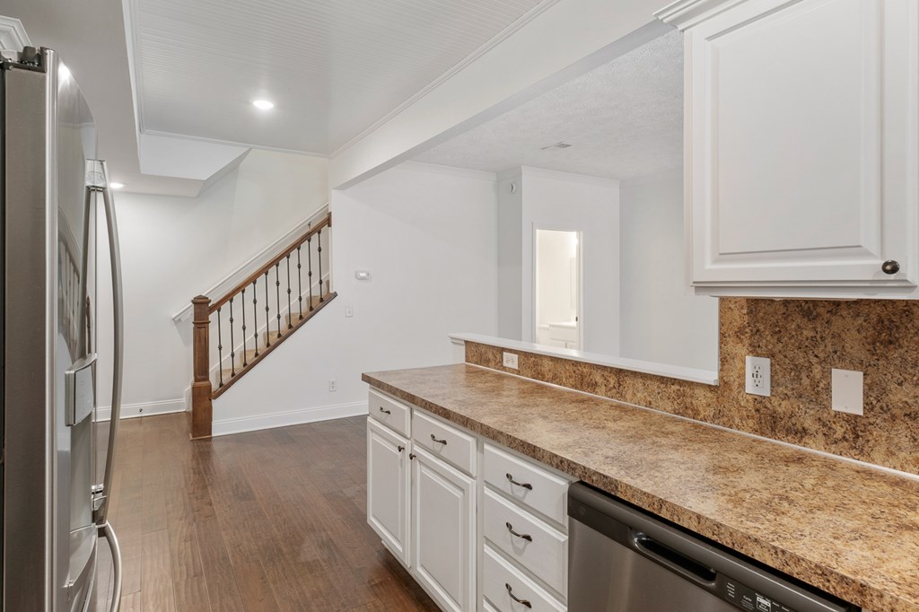 A kitchen with white cabinets and a granite countertop.