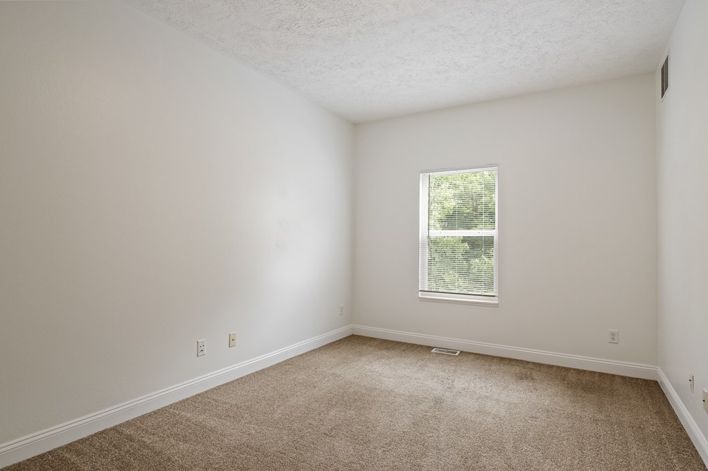 A room with a window and carpeted floor.