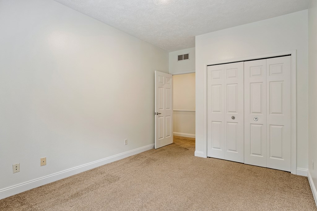 A room with a carpeted floor and a white door.
