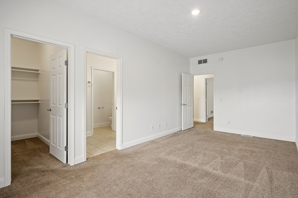 A large, empty room with carpeted flooring and white walls.