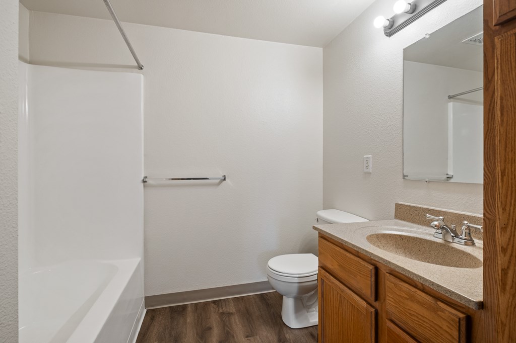 A white toilet sits in a small bathroom with a sink and mirror.