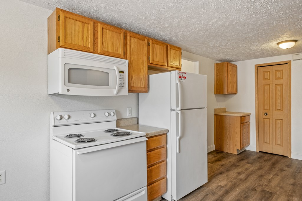 A white stove and microwave in a kitchen with wooden cabinets.
