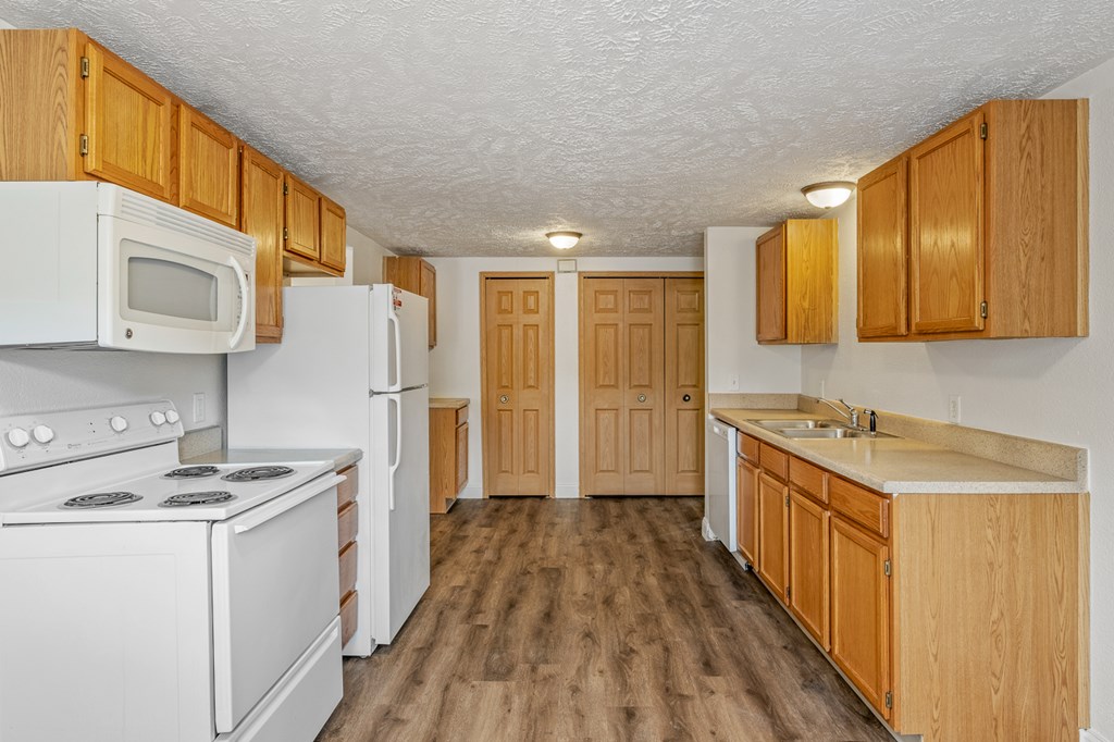 A kitchen with white appliances and wooden cabinets.