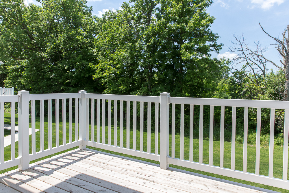 the view of the yard from the deck with a white fence