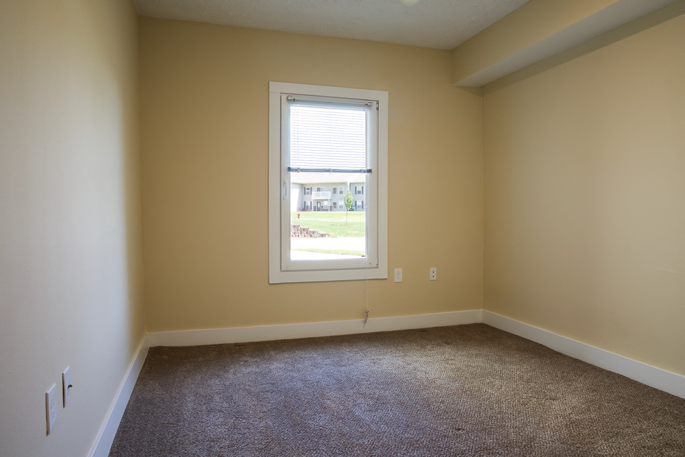 an empty room with a window and carpet