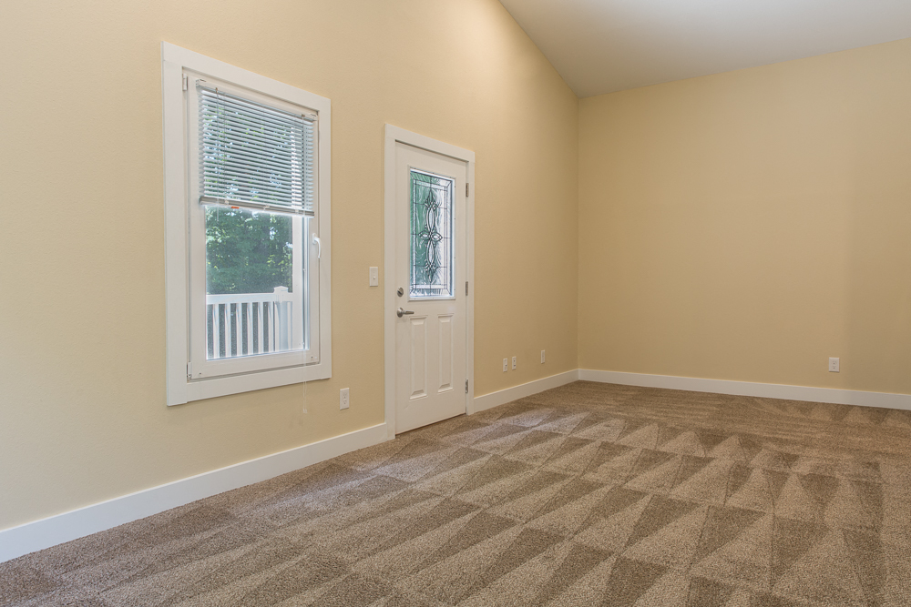 an empty living room with a door and a window