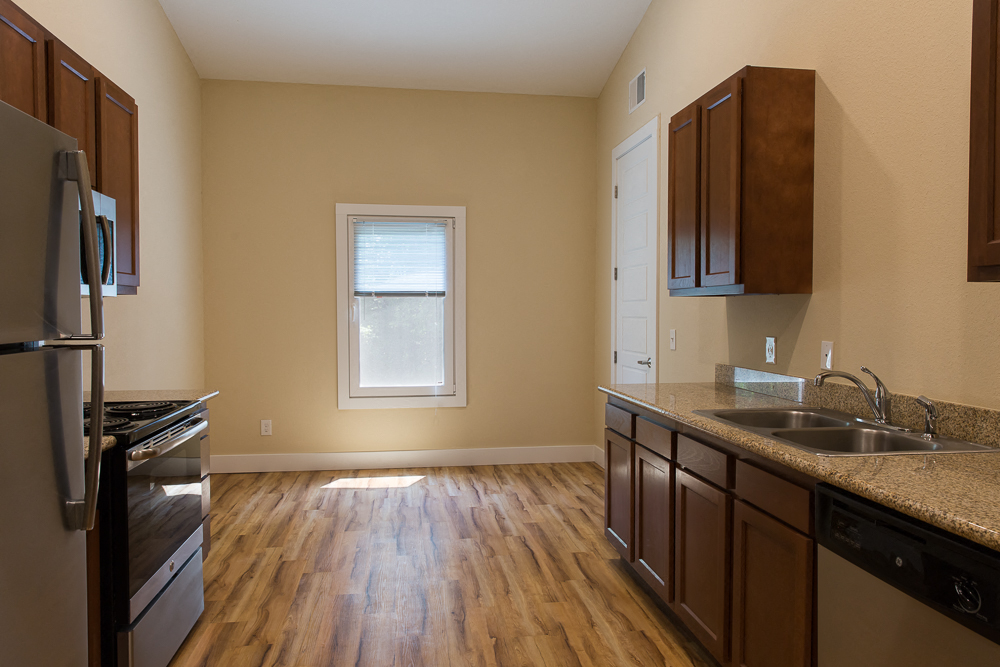 an empty kitchen with wood flooring and a window