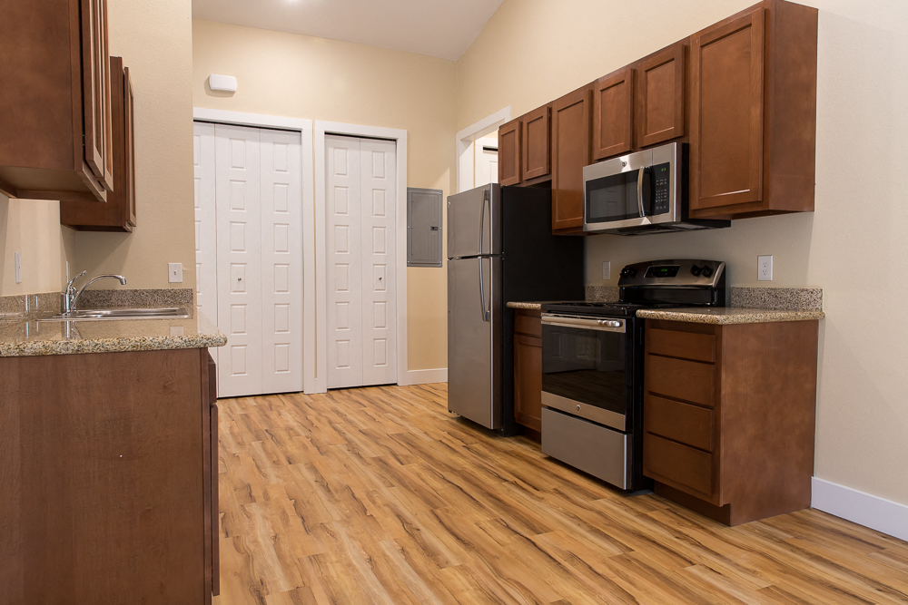 a kitchen with wood flooring and stainless steel appliances and