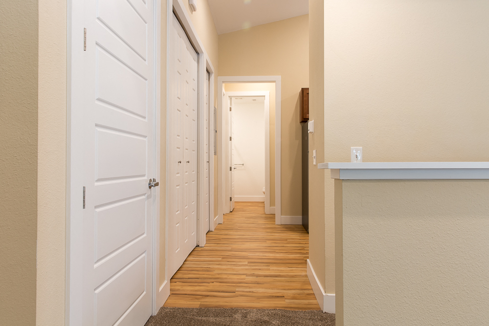a hallway with white doors and wood floors and a closet