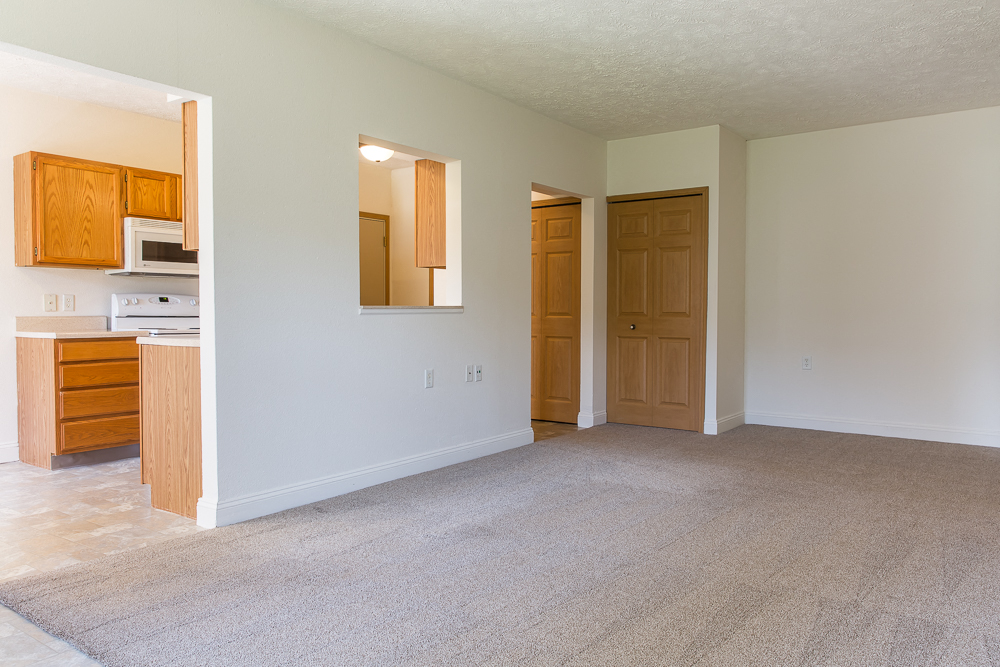 an empty living room and kitchen with a door to the bathroom