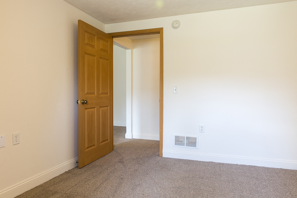 an empty bedroom with a door open to a hallway